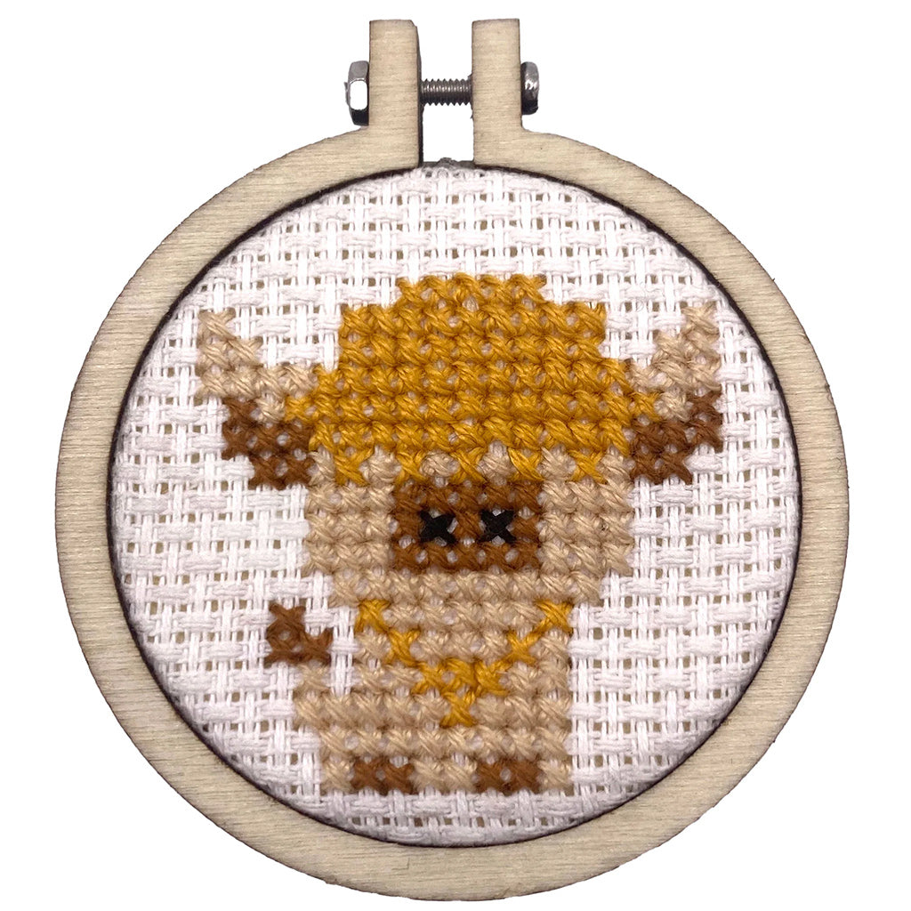 Cross-stitched design of a bear in an embroidery hoop on a white background