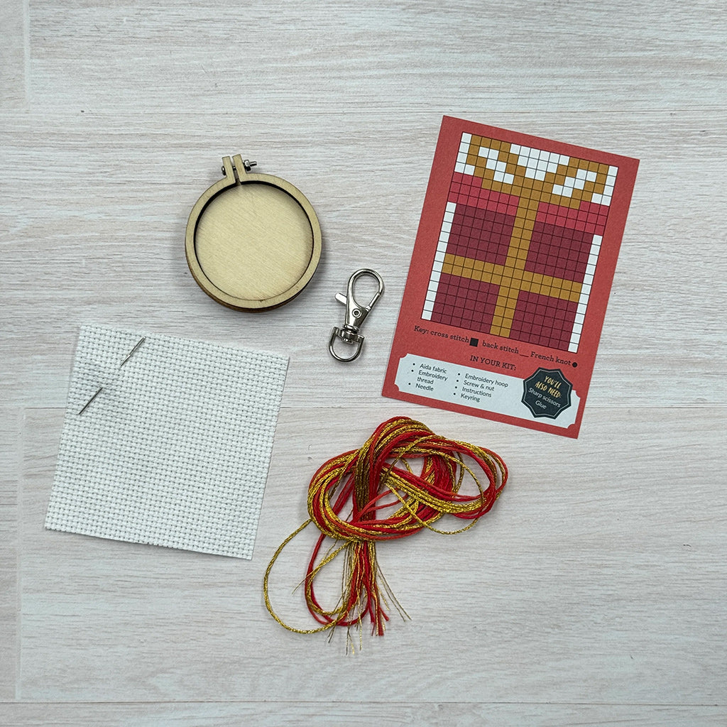 Embroidery kit with hoop, thread, needle, and pattern on a wooden surface