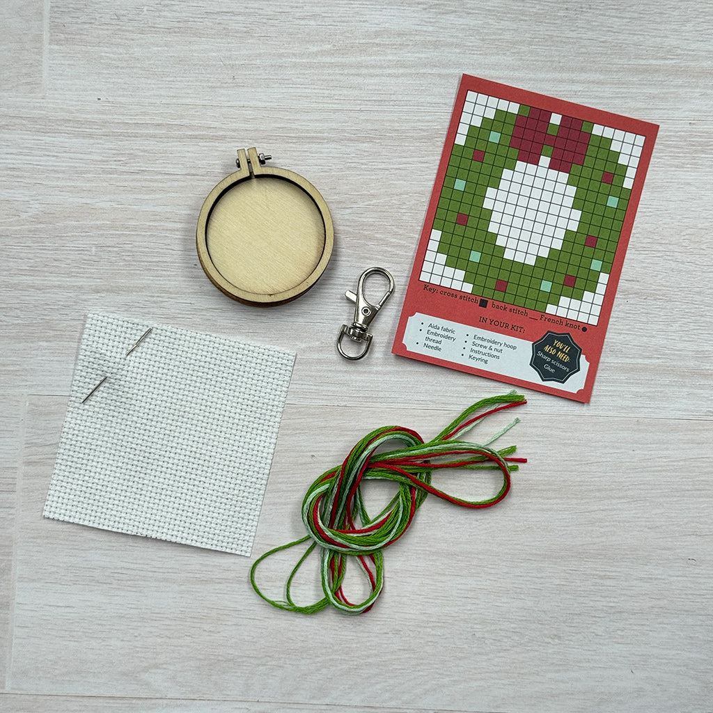 Embroidery hoop, fabric, thread, and pattern card on a wooden surface
