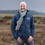Man standing in a field wearing a Spirit of Culloden tartan scarf with a blurred background