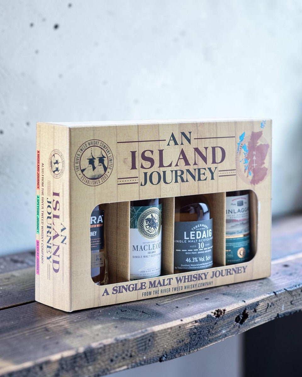 An Island Journey single malt whisky gift set containing four bottles presented in a light wood-textured box with a window display.