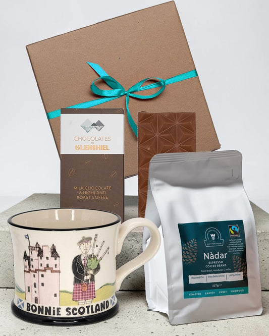 Gift set with a mug, chocolate bar, and coffee beans on a light background